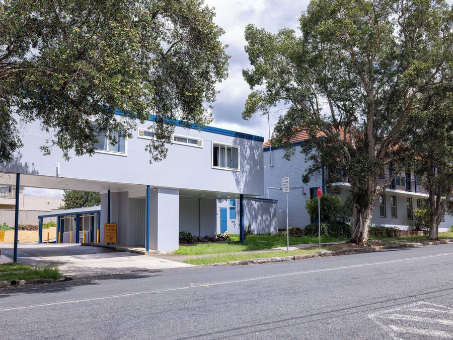 A building with a covered entrance, a blue door, and a parking area with yellow lines.
