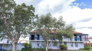 A two-story building with a balcony on the second floor, surrounded by trees. - Windsor Heritage Motel (Windsor)