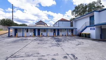 A building with a blue and white exterior, a covered parking area, and a staircase leading to a door.