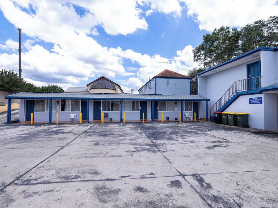 A building with a blue and white exterior, a covered parking area, and a staircase leading to a door.
