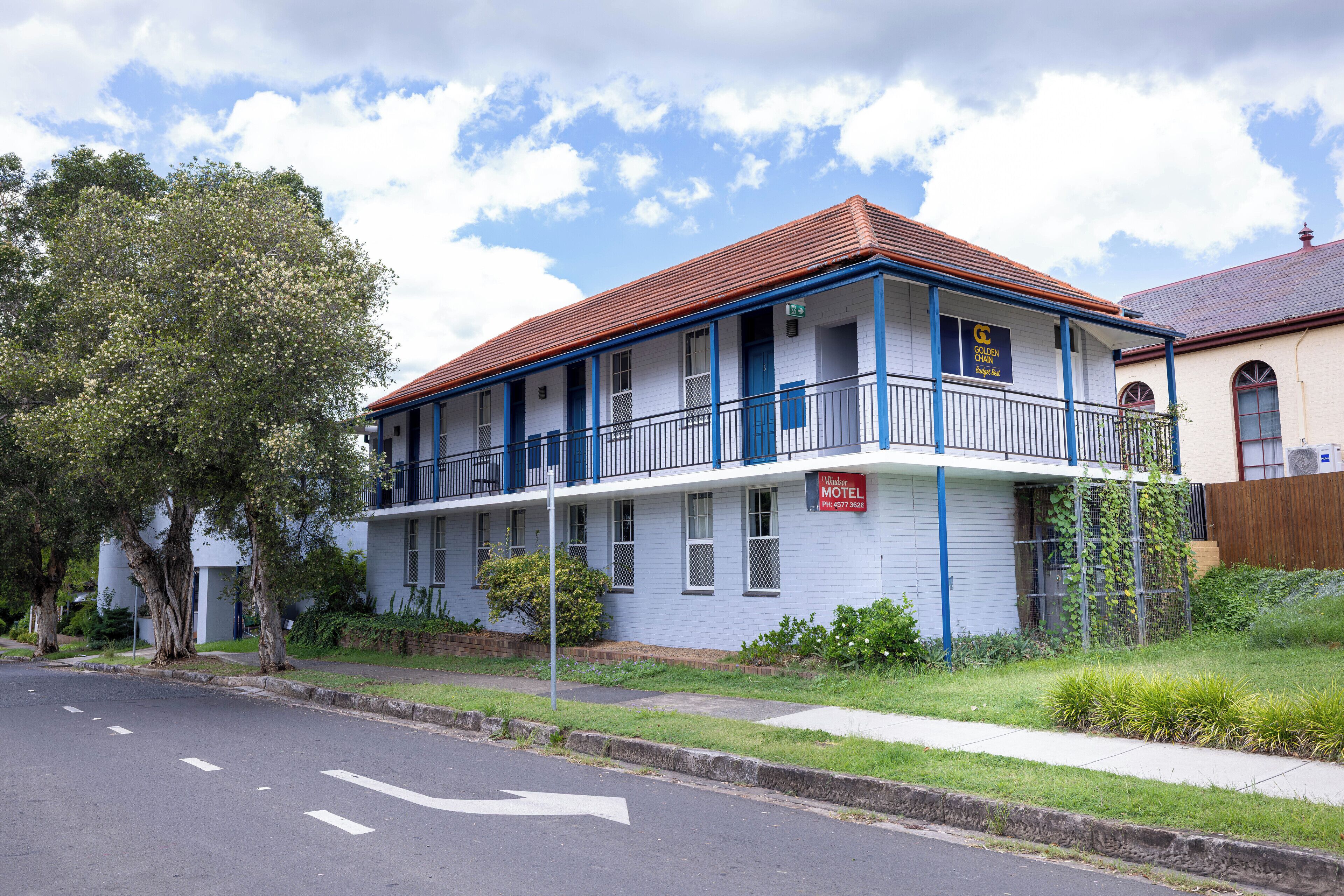 Un motel à deux étages, doté d’un balcon au deuxième étage, d’un toit rouge et d’une enseigne indiquant qu’il s’agit d’un motel.
