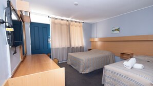 A hotel room with two beds, a desk, a mirror, and a door. - Windsor Heritage Motel (Windsor)