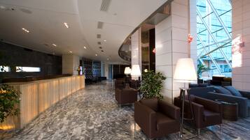 A modern lobby with a marble floor, seating area, and a reception desk.