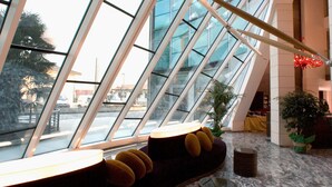 A modern interior with a curved seating area, a glass ceiling, and a view of the outside. - Antony Palace Hotel (Marcon)