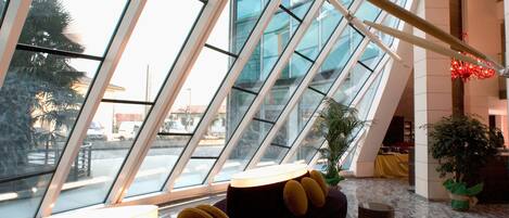 Un interior moderno con una zona de estar de curvas, un techo de cristal y vistas al exterior.