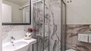 A modern bathroom with a marble sink, a glass-enclosed shower, and a white toilet.