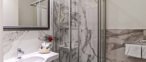 A modern bathroom with a marble sink, a glass-enclosed shower, and a white toilet.