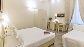 Habitación de hotel con dos camas, un escritorio, una silla, aire acondicionado y un cuadro en la pared.
