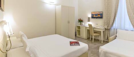Habitación de hotel con dos camas, un escritorio, una silla, aire acondicionado y un cuadro en la pared.