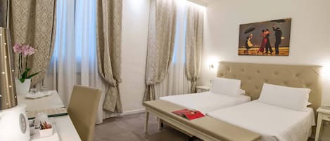 A hotel room with a bed, bedside tables, a desk with a chair, a coffee maker, and a painting on the wall.