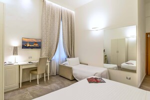 Camera d'albergo con scrivania, sedia, letto e uno specchio grande.