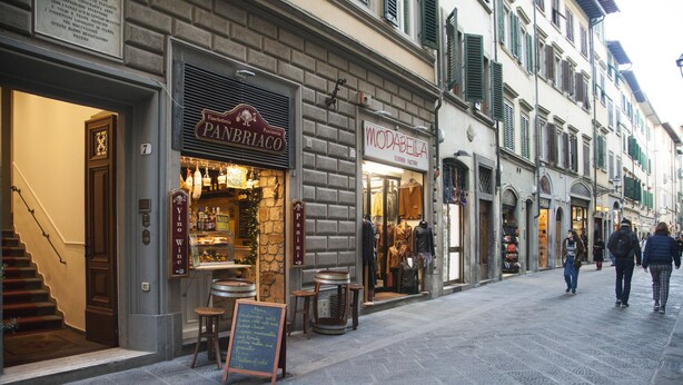 A street with storefronts, including a wine shop and a leather goods store.