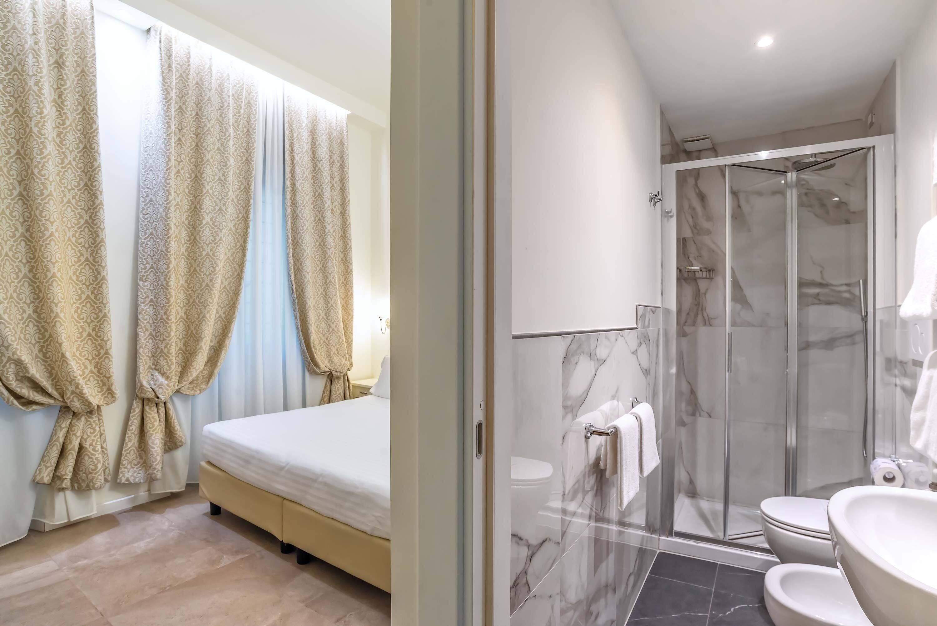 A hotel room with a bed, curtains, a bathroom with a shower, and a toilet.