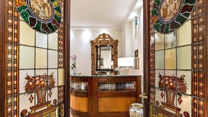 A reception area with a wooden counter, a large mirror, and a vase with a floral design.