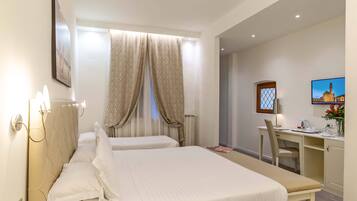A hotel room with two beds, a desk, and a chair.