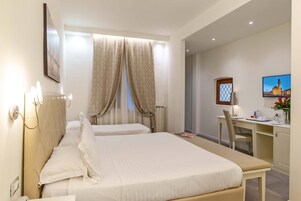 A hotel room with two beds, a desk, and a chair.