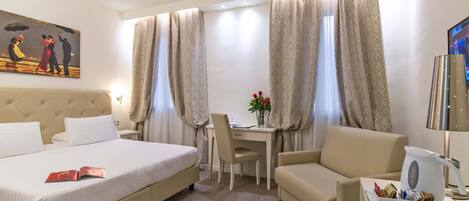 A hotel room with a bed, a desk, a chair, a sofa, a coffee maker, and a TV.