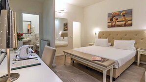 A hotel room with a large bed, a desk with a computer, a coffee maker, and a painting of a beach scene.