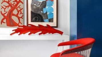 A modern room with a red chair, a white shelf with artwork, and a striped floor.