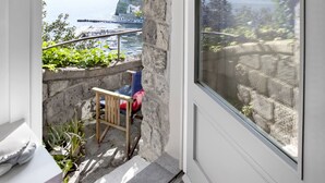A balcony with a stone arch, a chair, and a table. - Maison La Minervetta (Sorrento)