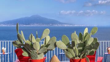 A terrace with red chairs, blue spherical decorations, and cacti.