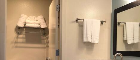 A bathroom with a toilet, a sink with a granite countertop, and a towel rack with towels.