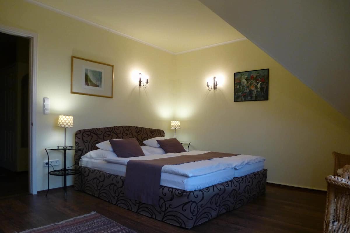 Een slaapkamer met een bed, twee nachtkastjes, een vloerkleed en wandlampen.