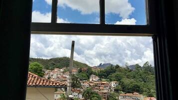 Finestra amb vista a una vila situada en un turó, amb edificis de teulades de terracota.