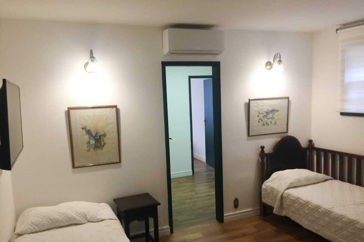 Un dormitorio con dos camas, una mesita pequeña y dos luces fijadas en la pared.
