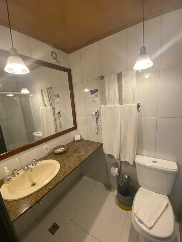 A bathroom with a sink, mirror, towel rack, and toilet.