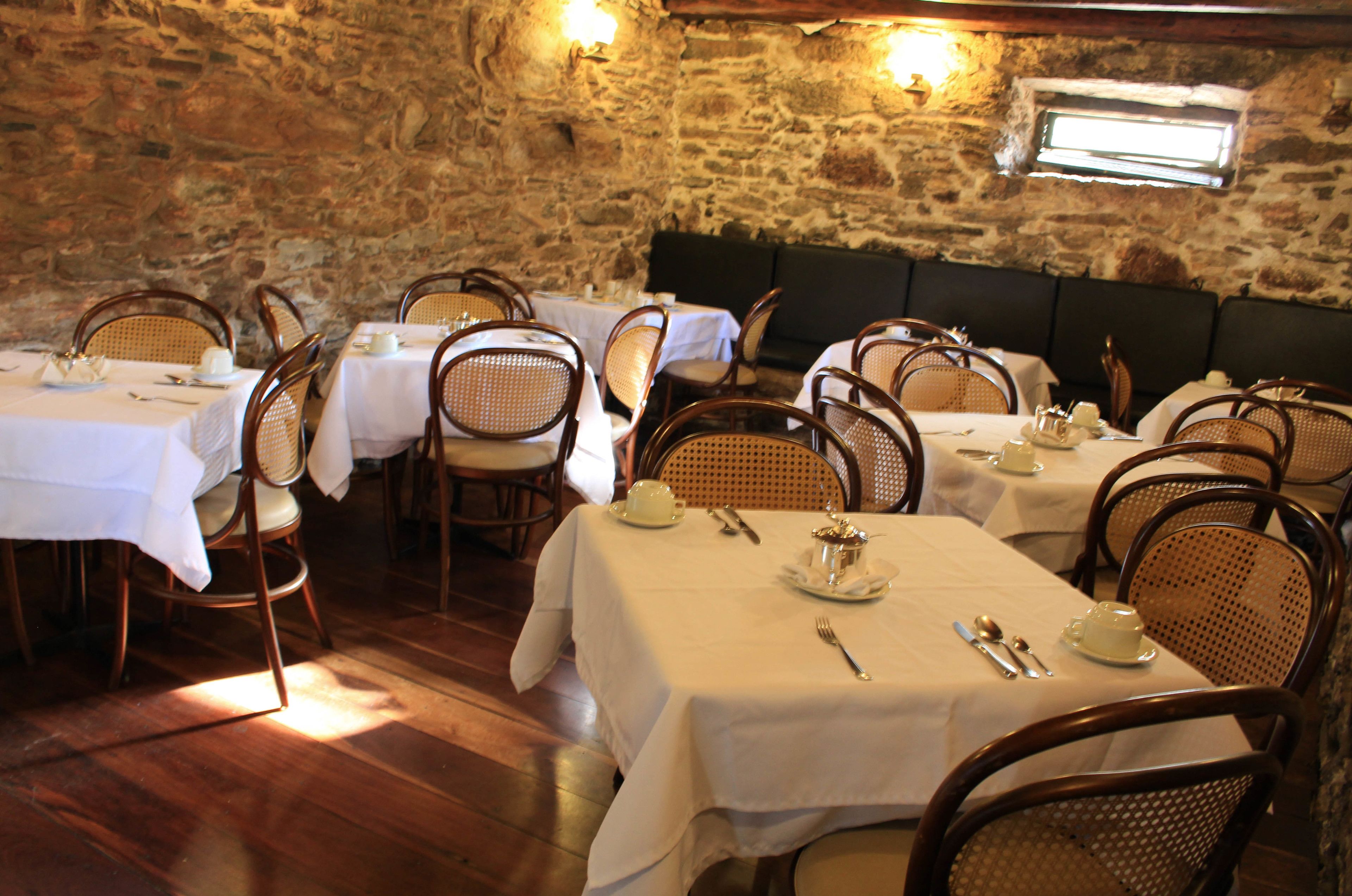 A restaurant with stone walls, wooden tables, and wicker chairs.