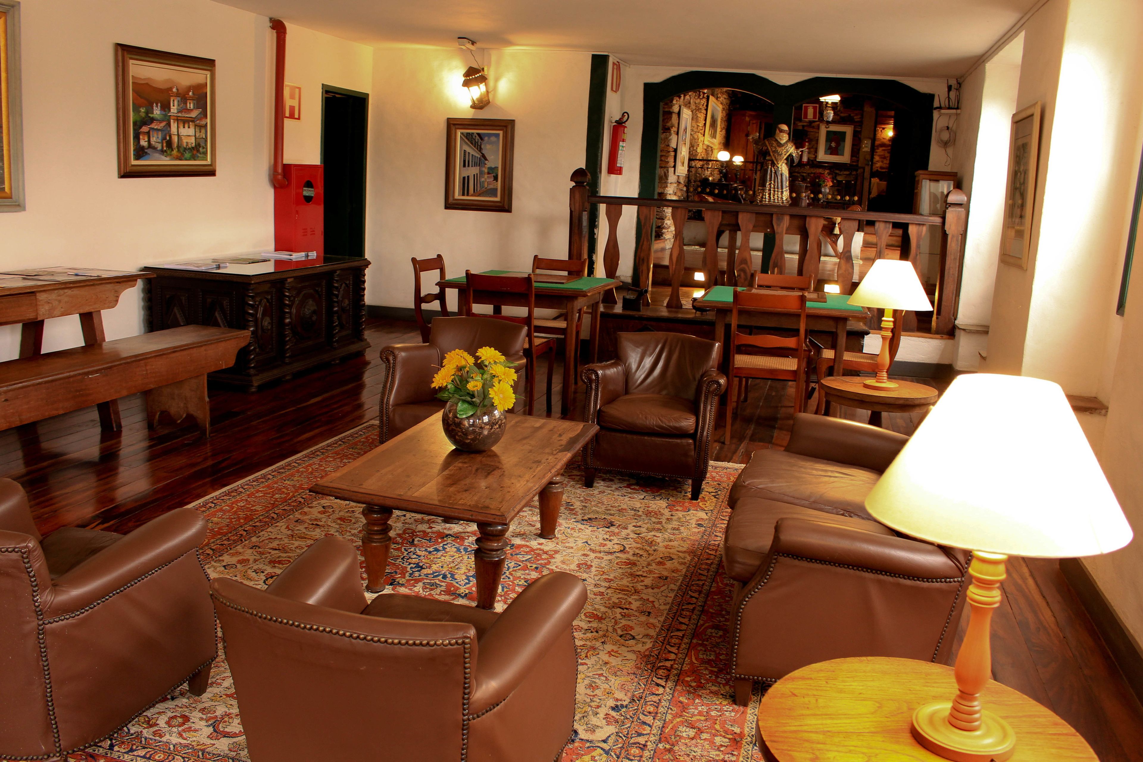 A traditional room with a wooden table, leather chairs, a patterned rug, and a lamp.