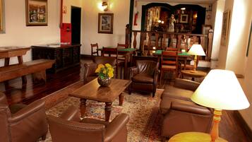 A traditional room with a wooden table, leather chairs, a patterned rug, and a lamp.