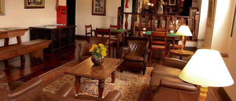 A traditional room with a wooden table, leather chairs, a patterned rug, and a lamp.
