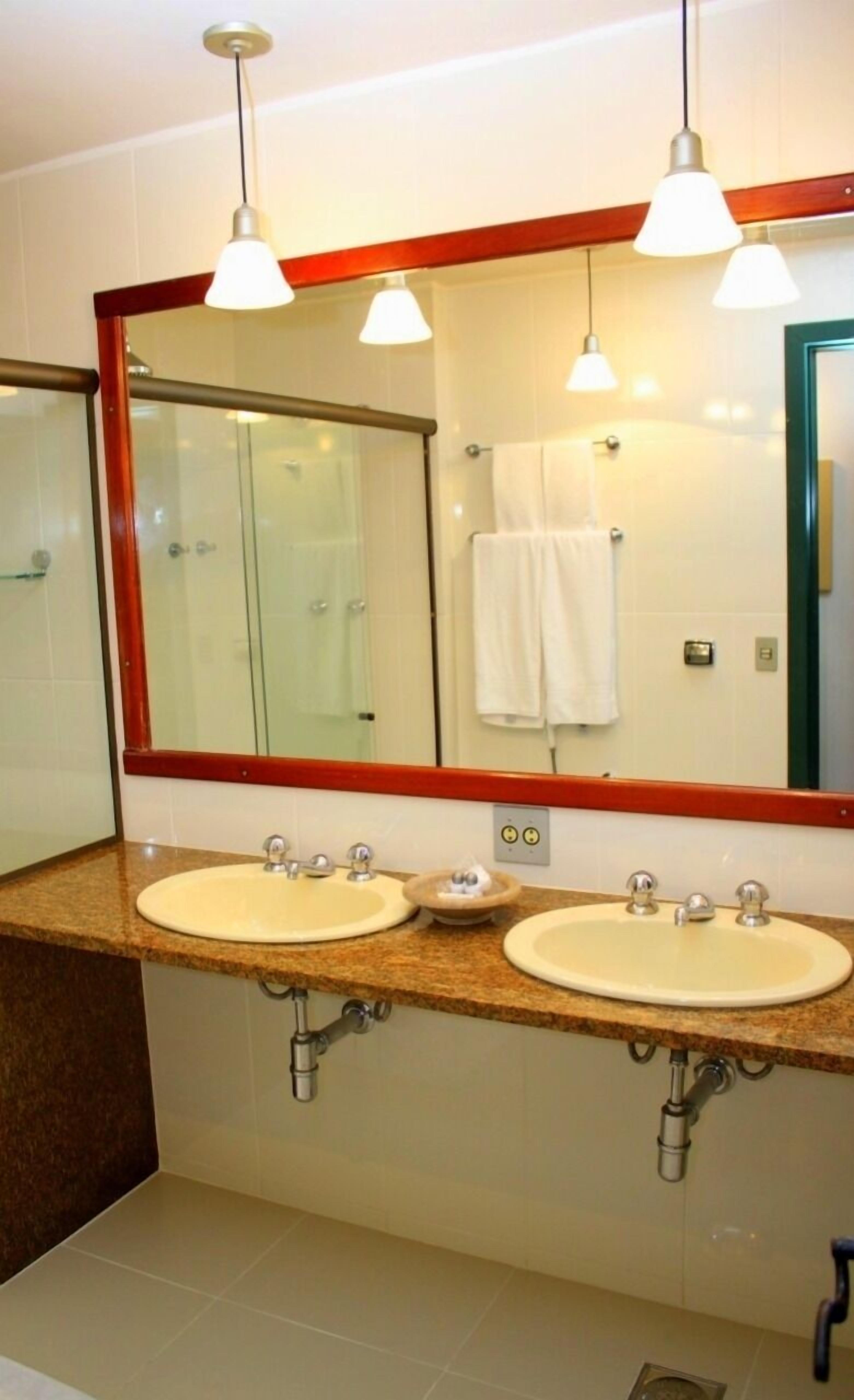 Un baño con dos lavamanos, un espejo grande e iluminación en el techo.