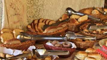 A table with baskets of bread and doughnuts, and tongs for serving.