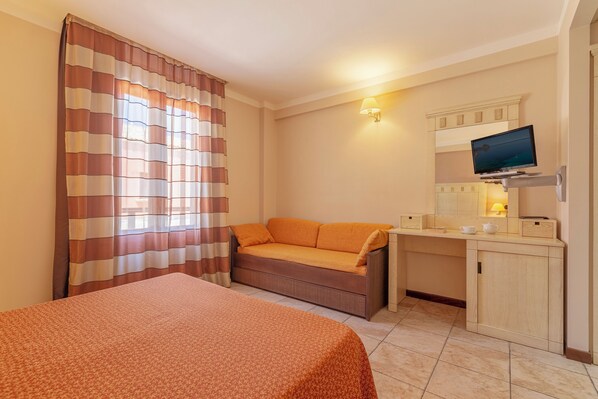 Una habitación con cama, sofá, escritorio, televisor y armario.