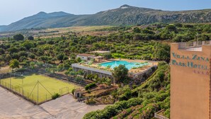 Villa Zina Park Hotel with a swimming pool, tennis court, and mountainous backdrop.