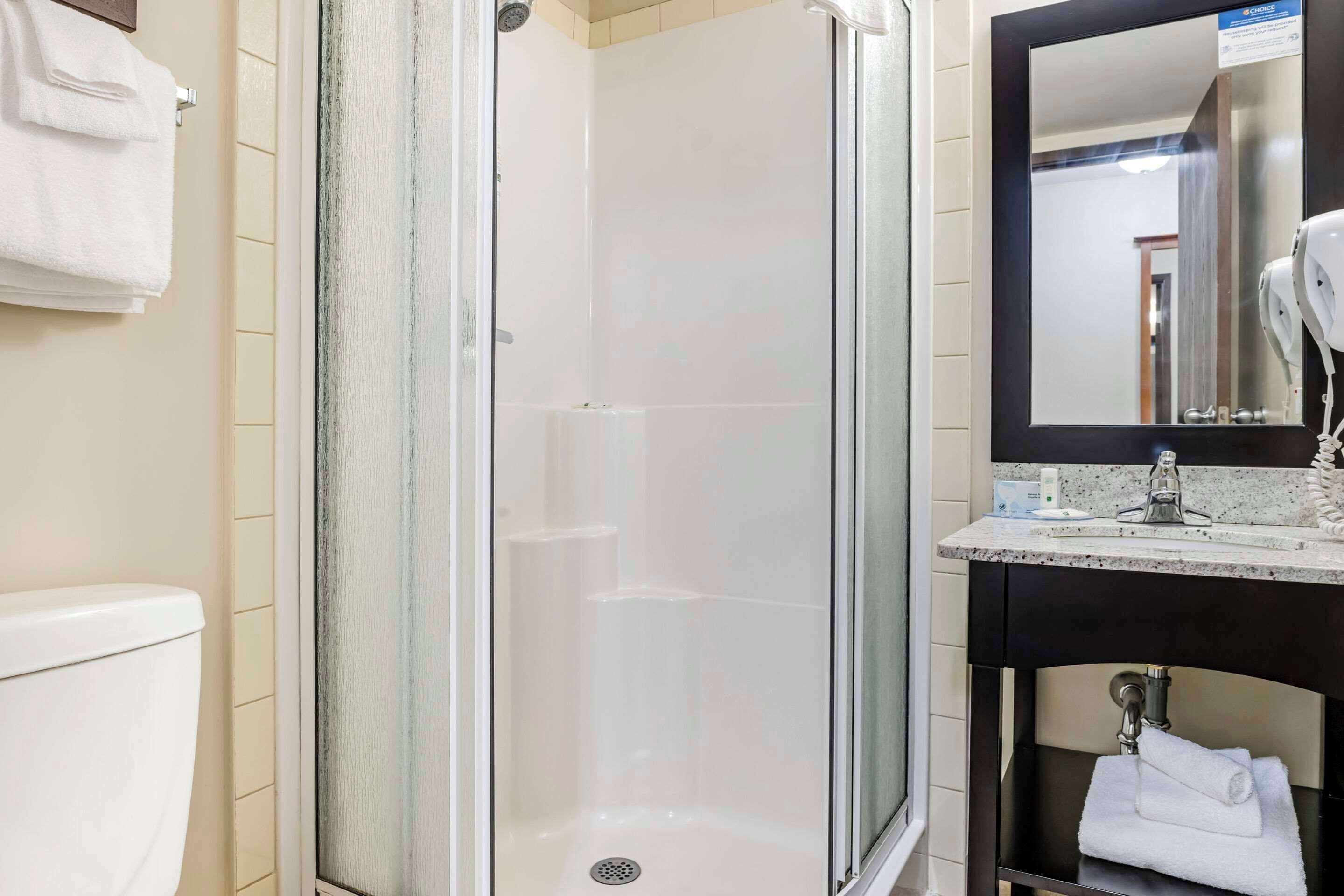 A bathroom with a glass-enclosed shower, a sink with a mirror, and a towel rack.