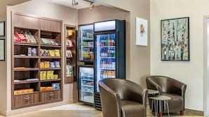 A lobby with a snack bar, a beverage refrigerator, and two leather armchairs.