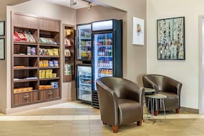 A lobby with a snack bar, a beverage refrigerator, and two leather armchairs. - Quality Inn Airport (Dieppe)
