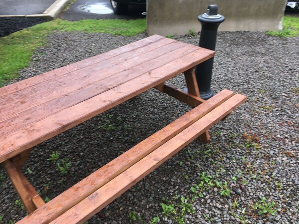 Una mesa de picnic de madera con bancos, sobre una superficie de grava.