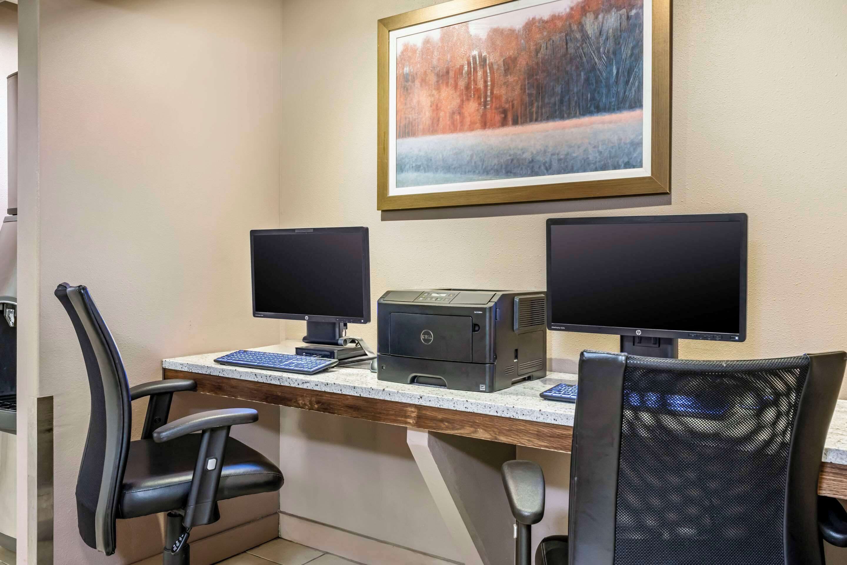 Un espacio de trabajo con dos monitores, una impresora y dos sillas.