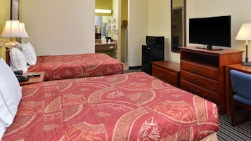 A hotel room with two beds, a TV, a desk, and a mirror.