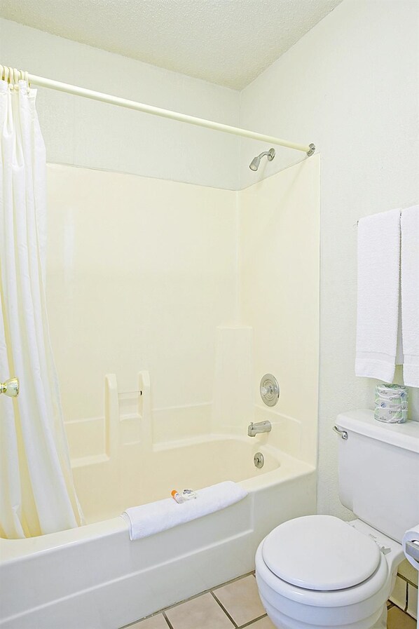 A bathroom with a bathtub, toilet, and a shower curtain.