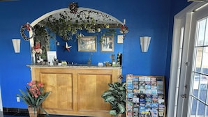 Uma área de recepção com parede azul, balcão de madeira, obras de arte emolduradas e um mural de avisos.