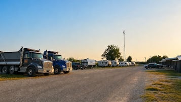 A gravel road with a row of RVs parked on one side and a large truck on the other.