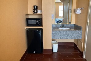 A compact bathroom with a microwave, refrigerator, sink, and a trash bin. - Apollo Lodge and RV Park (Fairfield)