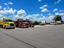 A parking lot with several trucks and a trailer.