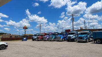 A parking lot with multiple trucks parked under a clear sky with scattered clouds.